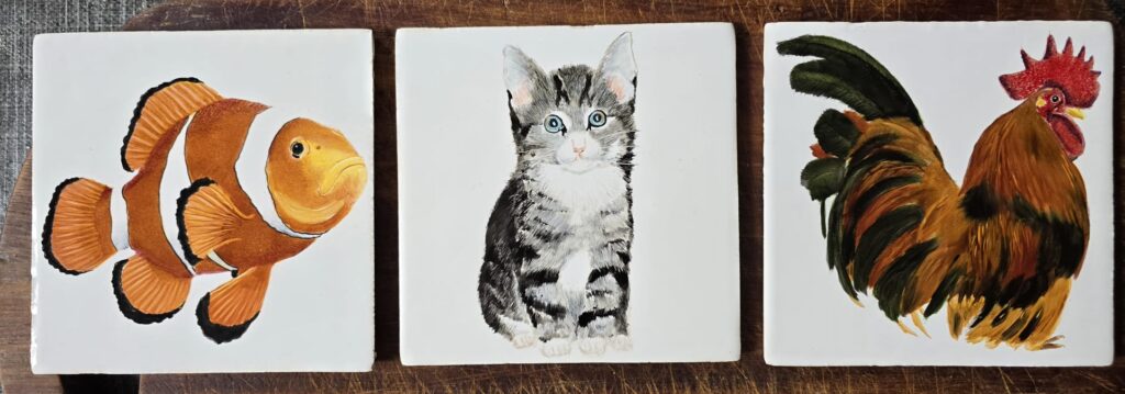 Drieluik met handgeschilderde tegels van een clownvis, een grijs kitten en een kleurrijke haan